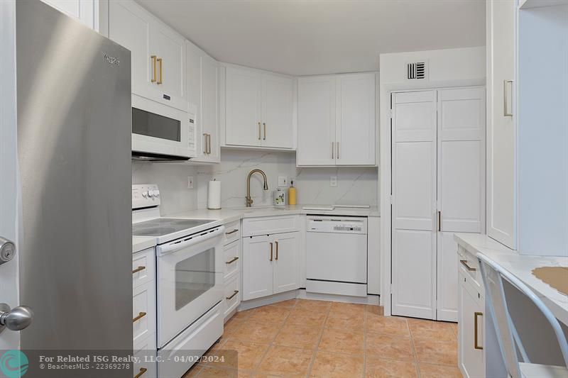 Full Size Stackable Washer & Dryer in Kitchen behind the white bifold door