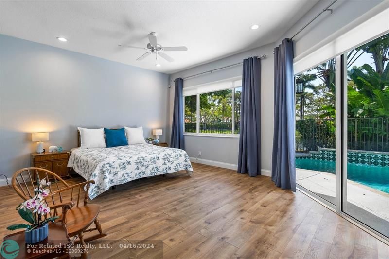 Primary bedroom boasts luxury vinyl flooring  and beautiful pool, patio and water views.