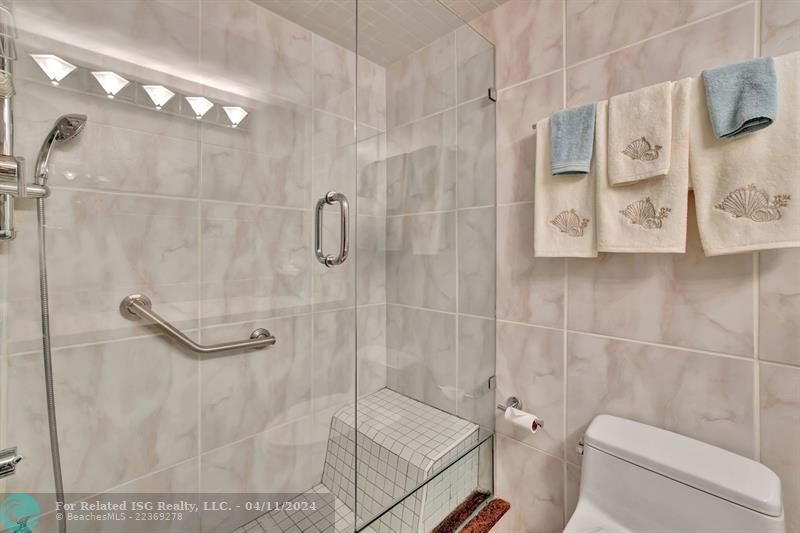 Guest Bathroom features a standing show and glass tub.