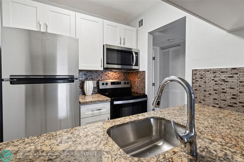 New cabinets, marble counters tile backsplash and stainless appliances