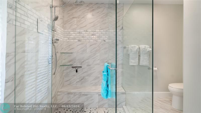 The oversized frameless glass shower boasts massaging body jets and a oversized rainfall showerhead.