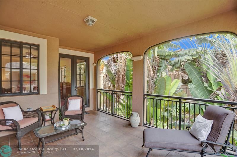 Generous covered tiled patio, surrounded by lush landscaping, creating a private oasis.