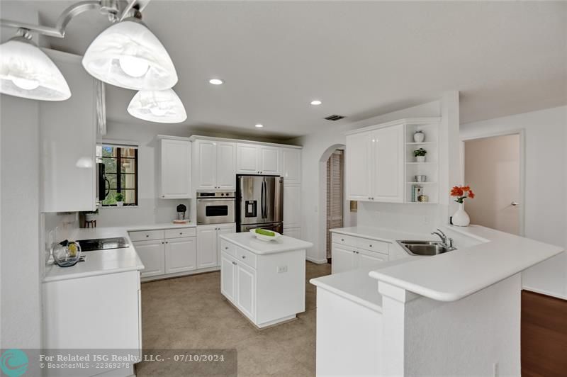 Huge crisp kitchen, stainless steel appliances, sleek white cabinetry with tons of storage, center island.