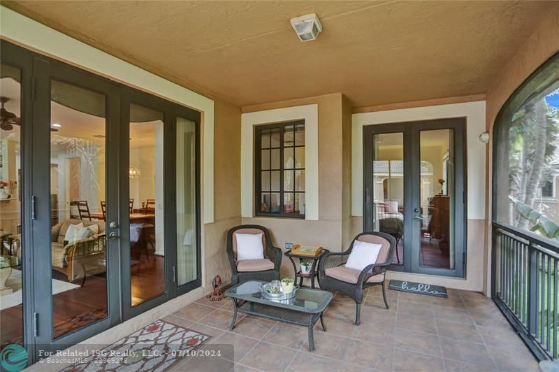 Impact glass French doors lead to this outdoor screened tile patio, creating a tranquil indoor-outdoor oasis.