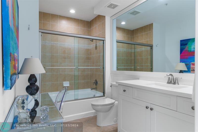 Spacious guest bath with tub/shower combo, modern white cabinets and quartz countertops