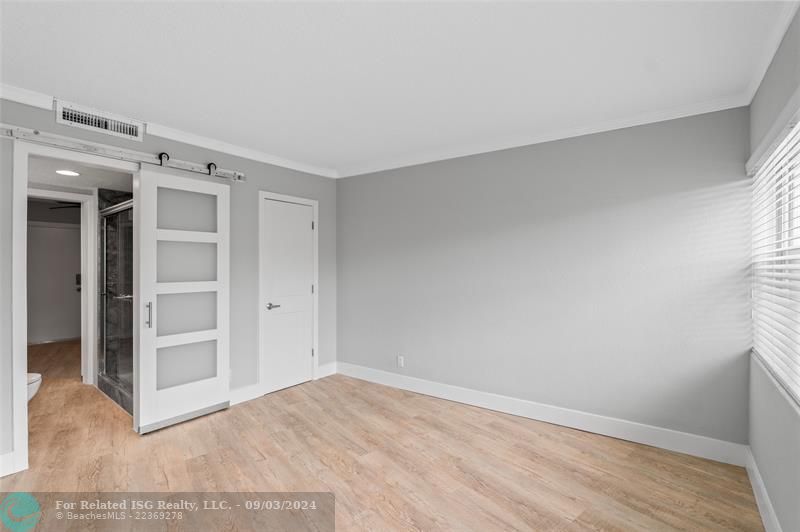 Access to the primary bathroom through the barn door & other door leads to the walk-in closet