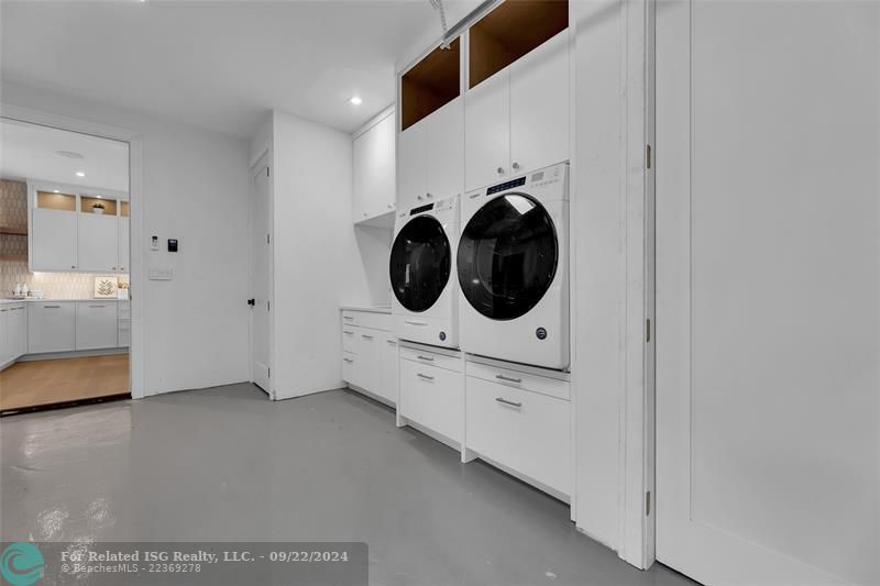 Front loading washer dryer located in the garage with folding area and possible tesla charger