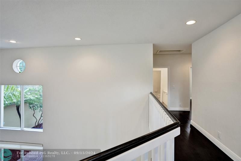 The hallway is very bright, thanks to the high ceiling and the sliding door that opens to the patio, leading to three bedrooms.