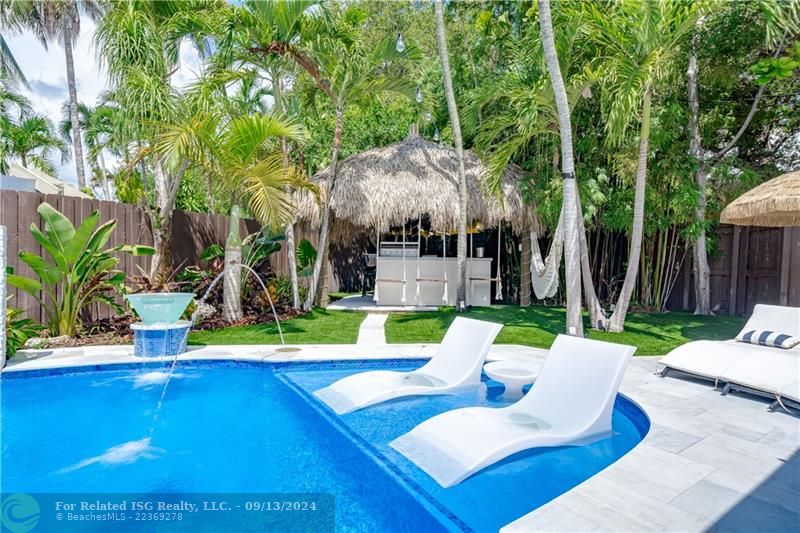 2 lounge chairs and center table inside of the pool to enjoy a cocktail under the sun