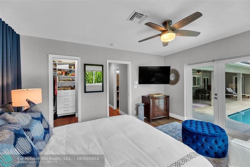 The walk in closet with built in cabinetry has a pocket door and is well lit.