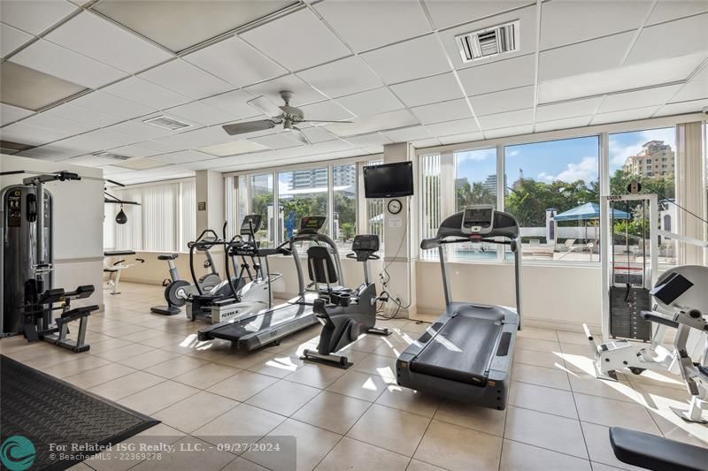 Spacious gym with yoga station, free weights, machines and a gorgeous view of the pool.