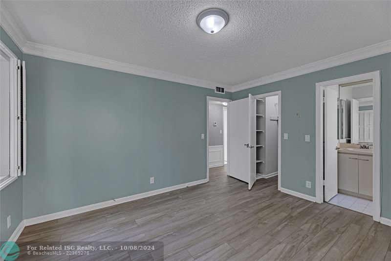 Primary bedroom with view into en-suite half bath and walk in closet