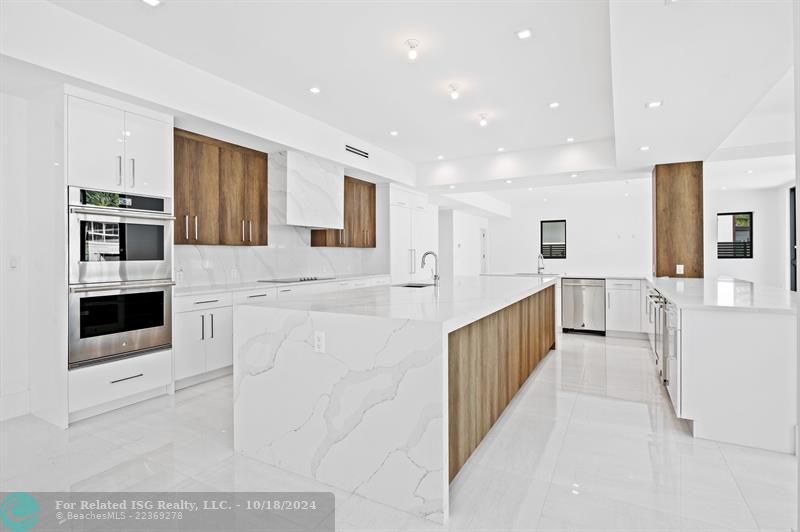 Custom kitchen with contrasting cabinetry, waterfall granite and huge island.