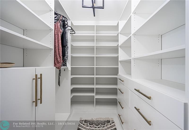 Master bedroom walk in closet with custom cabinetry