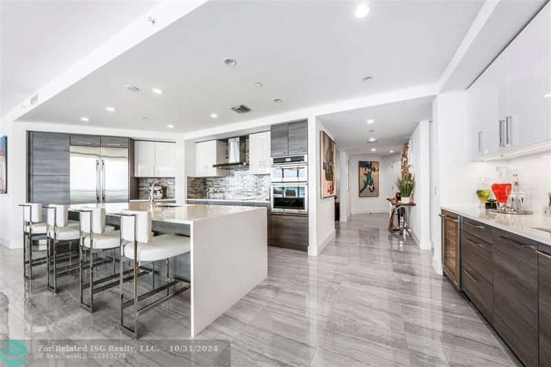 Wet bar + wine fridge in the gorgeous kitchen with Nolte cabinetry, lux backsplash, tons of storage, large waterfall island & amazing views!