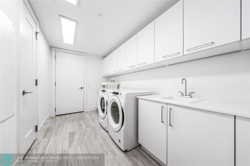 Huge laundry room with extensive cabinetry, storage, closet & sink.