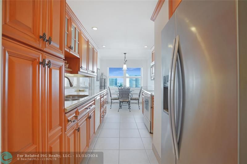 The galley kitchen has granite countertops and custom wood cabinets.