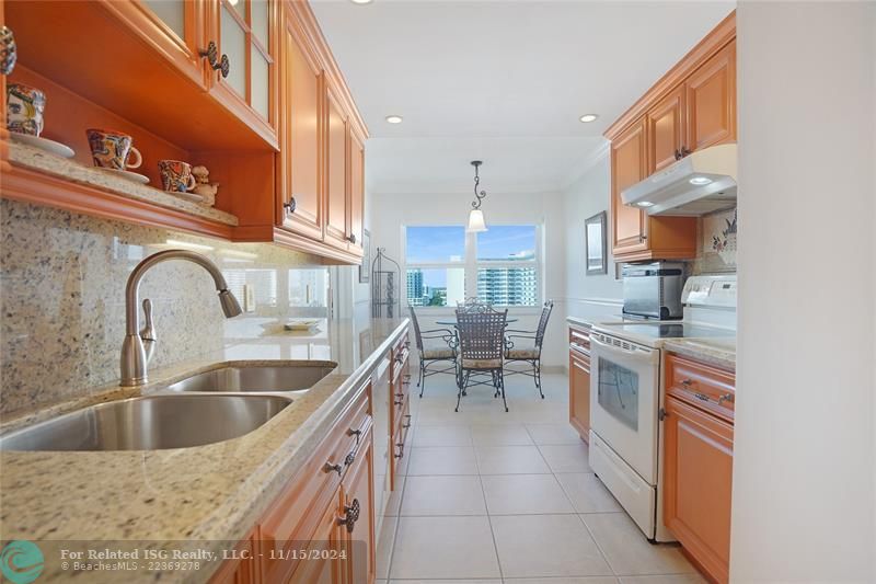 The galley kitchen has granite countertops and custom wood cabinets.