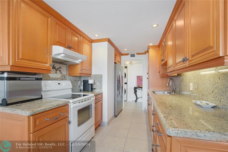 The galley kitchen has granite countertops and custom wood cabinets.