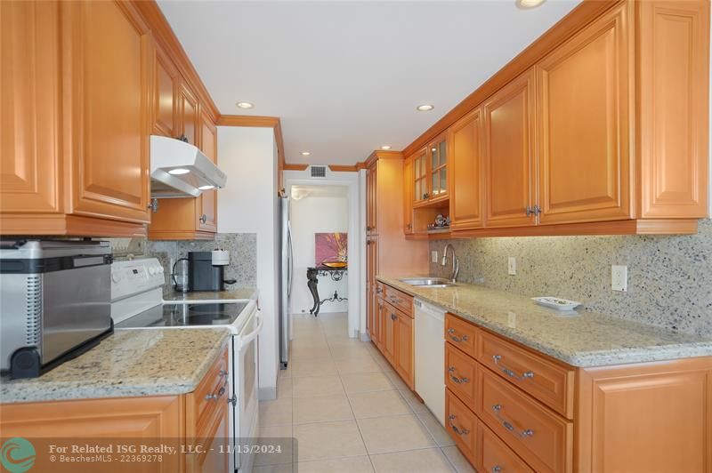 The galley kitchen has granite countertops and custom wood cabinets.