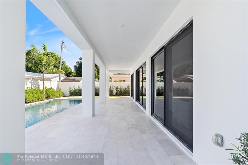 East view of covered patio and pool deck with screened sliders all along the patio making it great for entertaining.