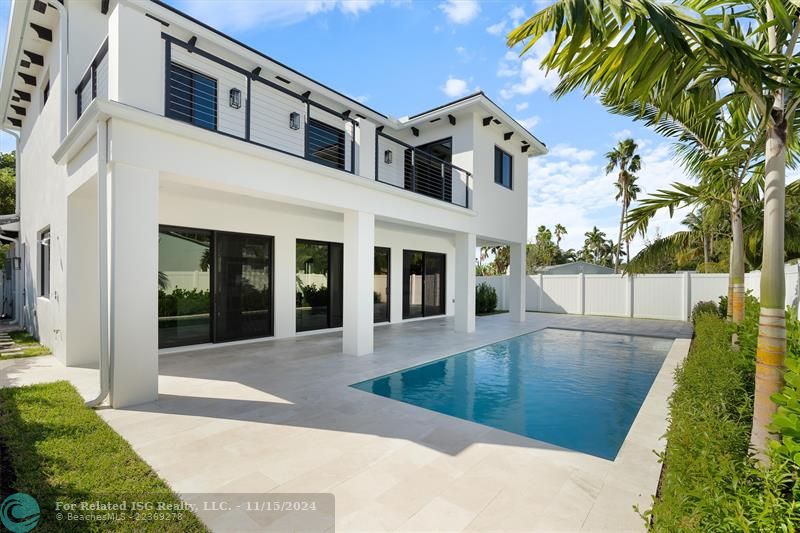 View of the back of this beautifully designed home.  You can see the large balcony. Generous sized pool and deck area along with walls of screened sliders bringing the outdoors to the inside.