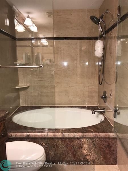 The primary bathroom has a large marble enclosed soaking tub.