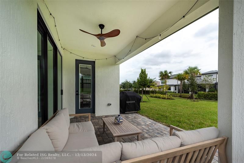 Covered outdoor patio with pavered floors wiht view to the back yard