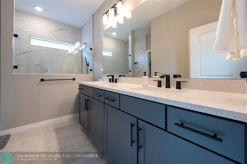 primary bathroom with quartz countertops, doubl sinks, walk-in shower