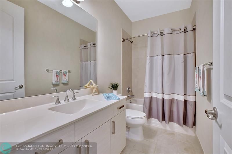 Guest bath features an extra long counter height vanity and a tub for the kiddos.