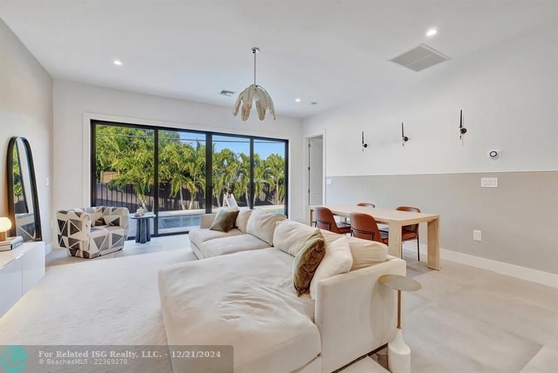 The living room effortlessly transitions to the private backyard pool area through the high-impact dual French sliding doors, perfect for indoor-outdoor entertaining.