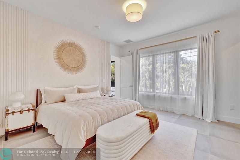 The primary bedroom is a serene retreat with an en-suite bathroom, custom walk-in closet, and a large window providing an abundance of natural light.