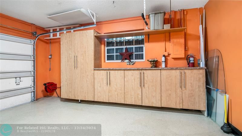 Well organized garage with extra storage built in and work counter with cabinets